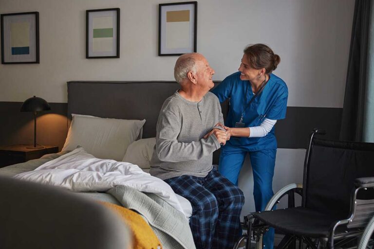 Staff assisting elderly residents during a winter storm evacuation with blankets and medical equipment.