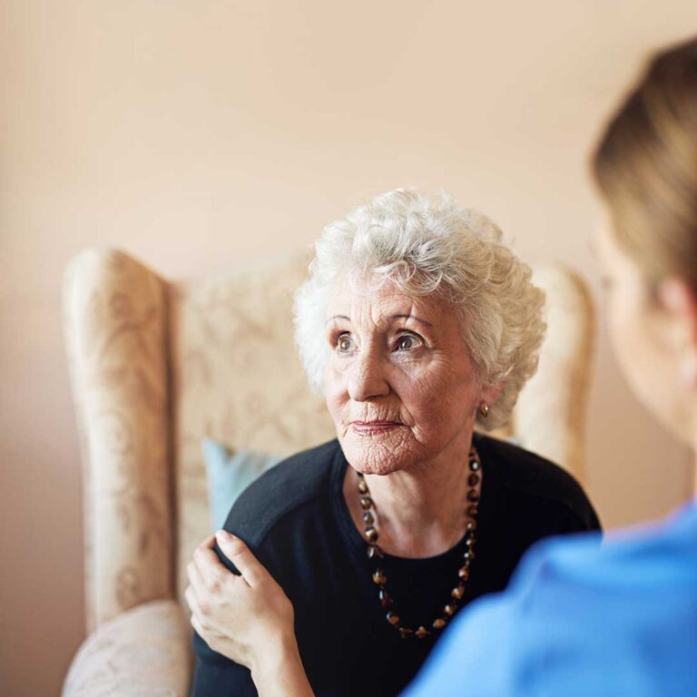 Older adults and family members tour a bright assisted living apartment with a staff guide.